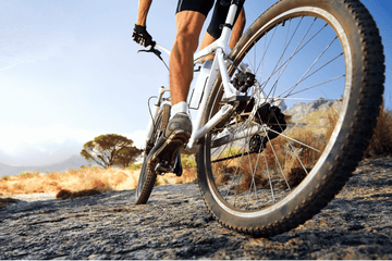 Close-up of a rider on an electric mountain bike navigating rugged terrain, highlighting the power and agility of e-bikes on off-road trails under a clear blue sky.