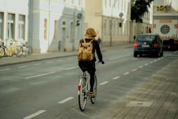 Woman cycling through a quiet European city street with a backpack, commuting calmly in a dedicated bike lane.