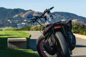 Rear view of a fat tyre electric bike with cargo bags on a scenic mountain trail – perfect for off-road riding and adventure cycling from Glide & Gear UK.