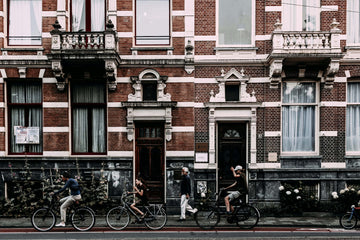 Cyclists riding through a European city street with historic buildings, showcasing urban commuting on bikes using cyclescheme.
