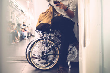 Commuter with a folding electric bike on public transport, illustrating the convenience and portability of foldable e-bikes for seamless urban commuting.