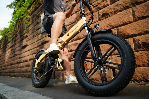 Rider on an Ado electric bike with chunky all-terrain tyres, captured against a brick wall. Available at Glide & Gear, an online e-bike retailer. The Ado e-bike offers sleek design, urban mobility, and a powerful performance for a smooth ride.