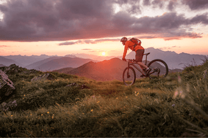 Rider on an electric mountain bike exploring a scenic mountain trail at sunset, showcasing the adventure and versatility of e-bikes in beautiful off-road environments.