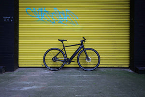 Falcon electric hybrid bike parked against a yellow graffiti wall, featuring a lightweight frame and powerful motor for city commuting.