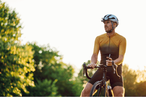 Male cyclist in a sleek cycling jersey riding a road bike during a scenic sunset. Explore Glide & Gear's collection of high-performance electric road bikes and cycling gear, perfect for speed, endurance, and long-distance rides.