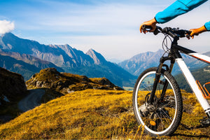 Electric hybrid bike on a mountain trail with stunning panoramic views of rugged peaks, emphasising the bike's performance and versatility in high-altitude terrain.