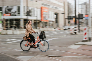 Woman riding an urban electric bike through the city streets, illustrating the practicality and style of electric bikes for city commuting.