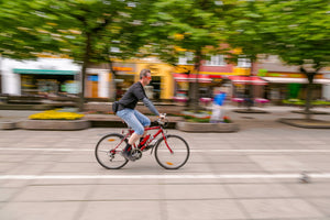 Man riding an electric bike through a vibrant city square, illustrating the ease and speed of electric bikes for urban commuting.